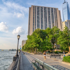 a riverwalk with a building, trees and river